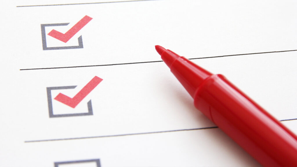 校正用紙を赤ペンで確認しながらチェックリストを埋めている手元のイメージ