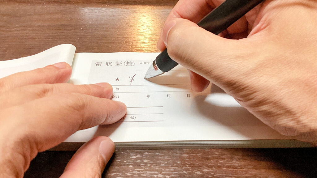 複写式領収書のミシン目を切り離して渡すイメージ画像